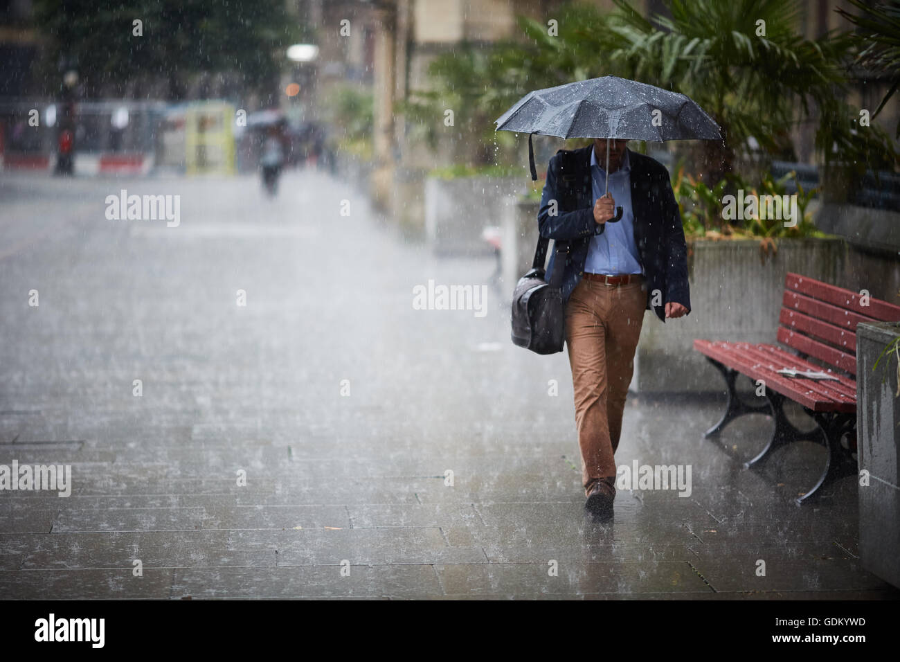 Las fuertes lluvias en el centro de la ciudad de Manchester lluvia llueven pour húmedo empapado en remojo a través de un paraguas de rebote de pavimento de piso Foto de stock