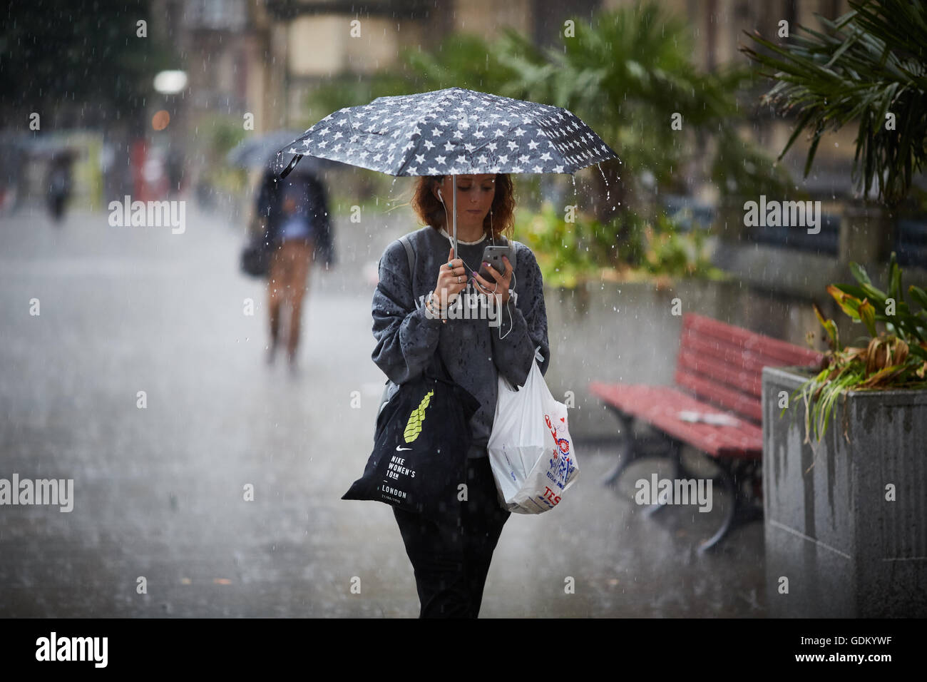 Las fuertes lluvias en el centro de la ciudad de Manchester lluvia llueven pour húmedo empapado en remojo a través de un paraguas de rebote de pavimento de piso Foto de stock