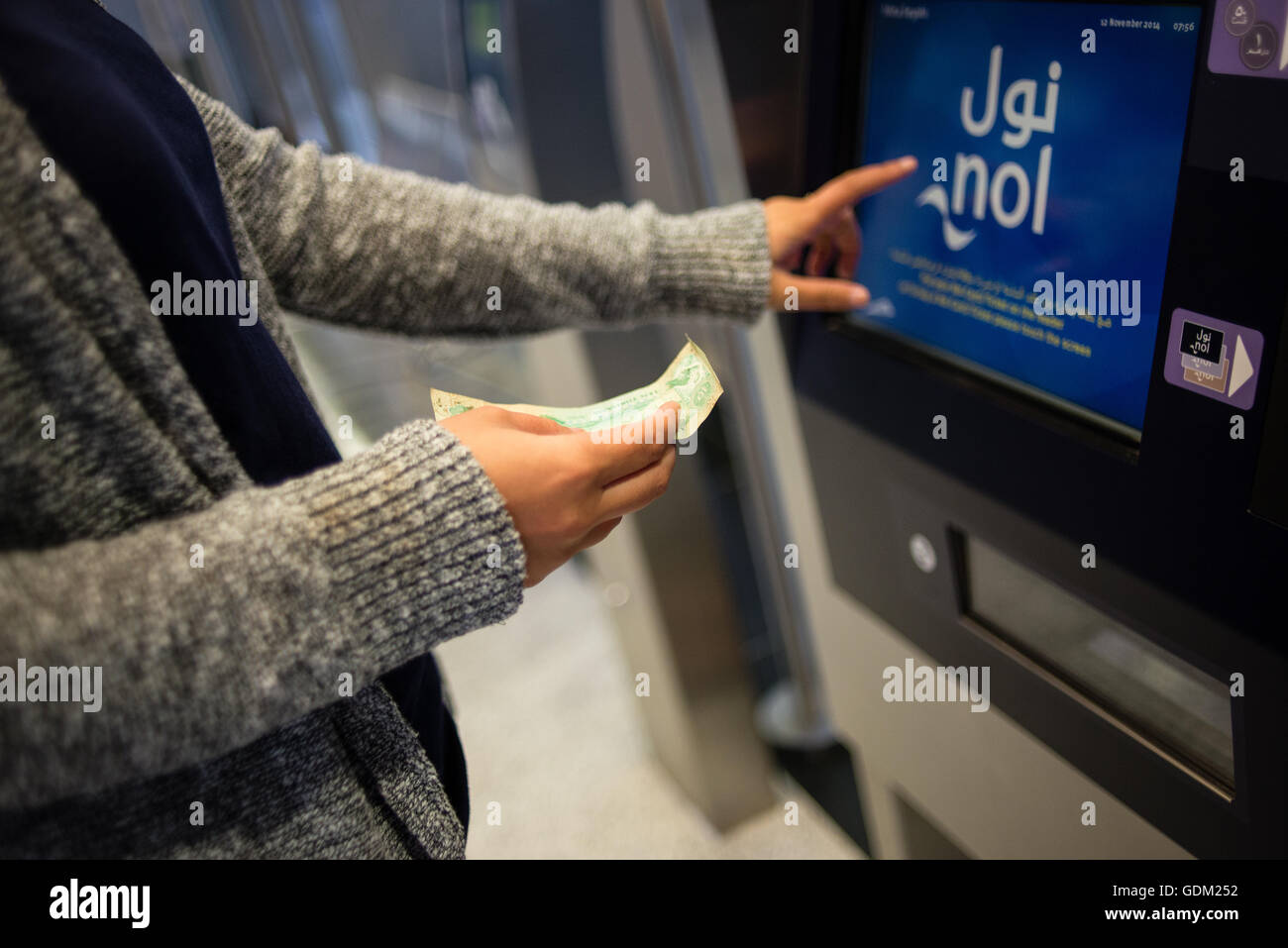 Una mujer la inserción de dinero en una máquina de billetes, Dubai, EAU. Foto de stock