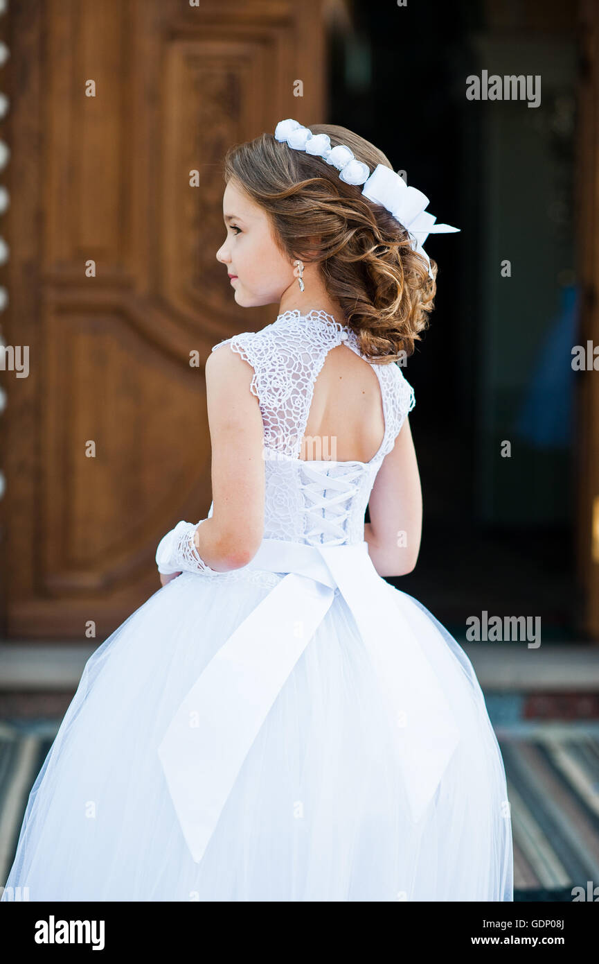 Retrato de cute little girl en vestido y corona en la primera comunión la puerta de la iglesia de fondo Fotografía de Alamy