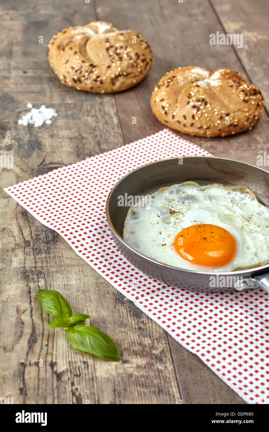 Huevo frito en una sartén con rollos de grano completo. Foto de stock