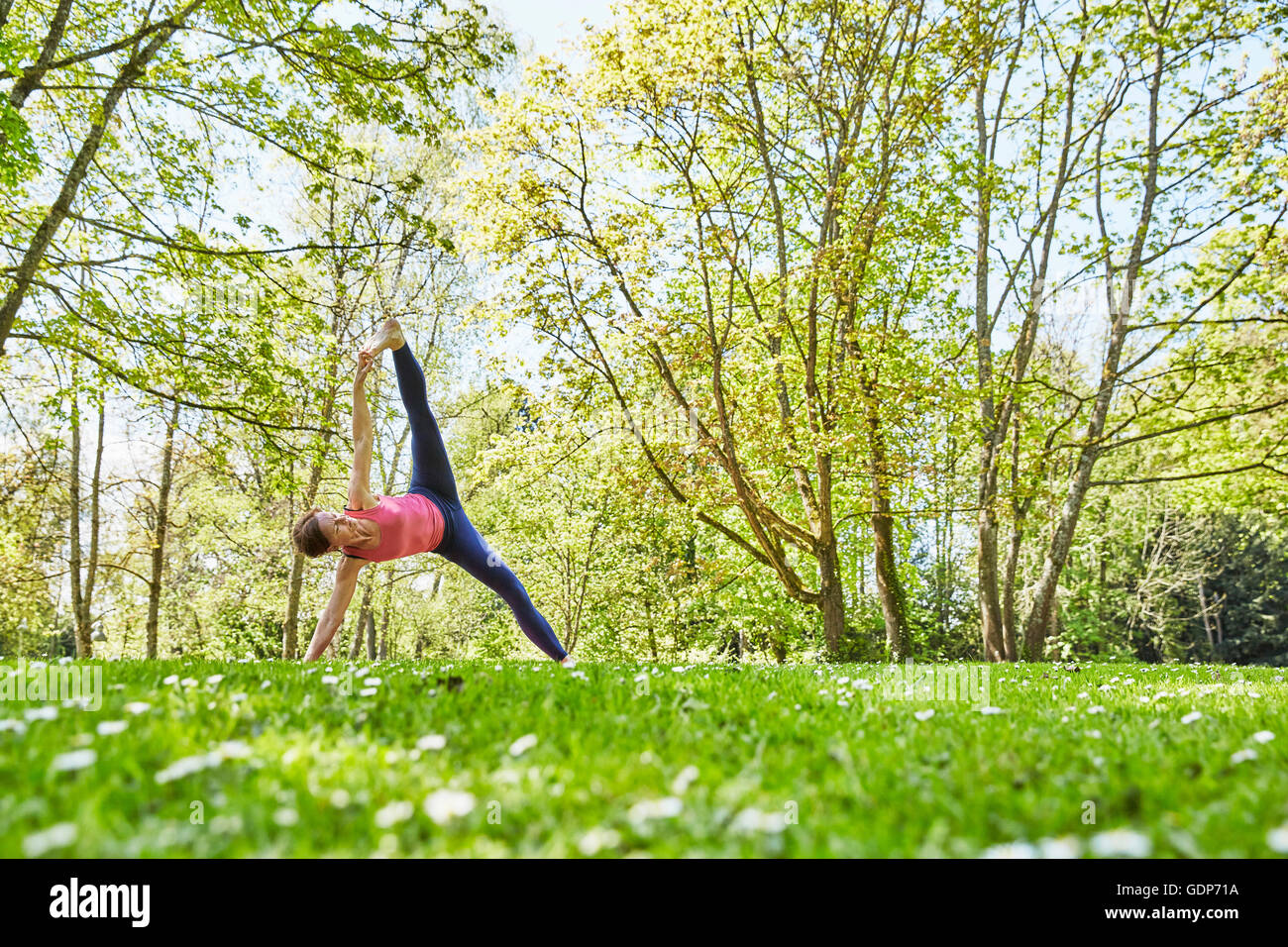 Mujer el brazo y la pierna levantada en posición de yoga Foto de stock