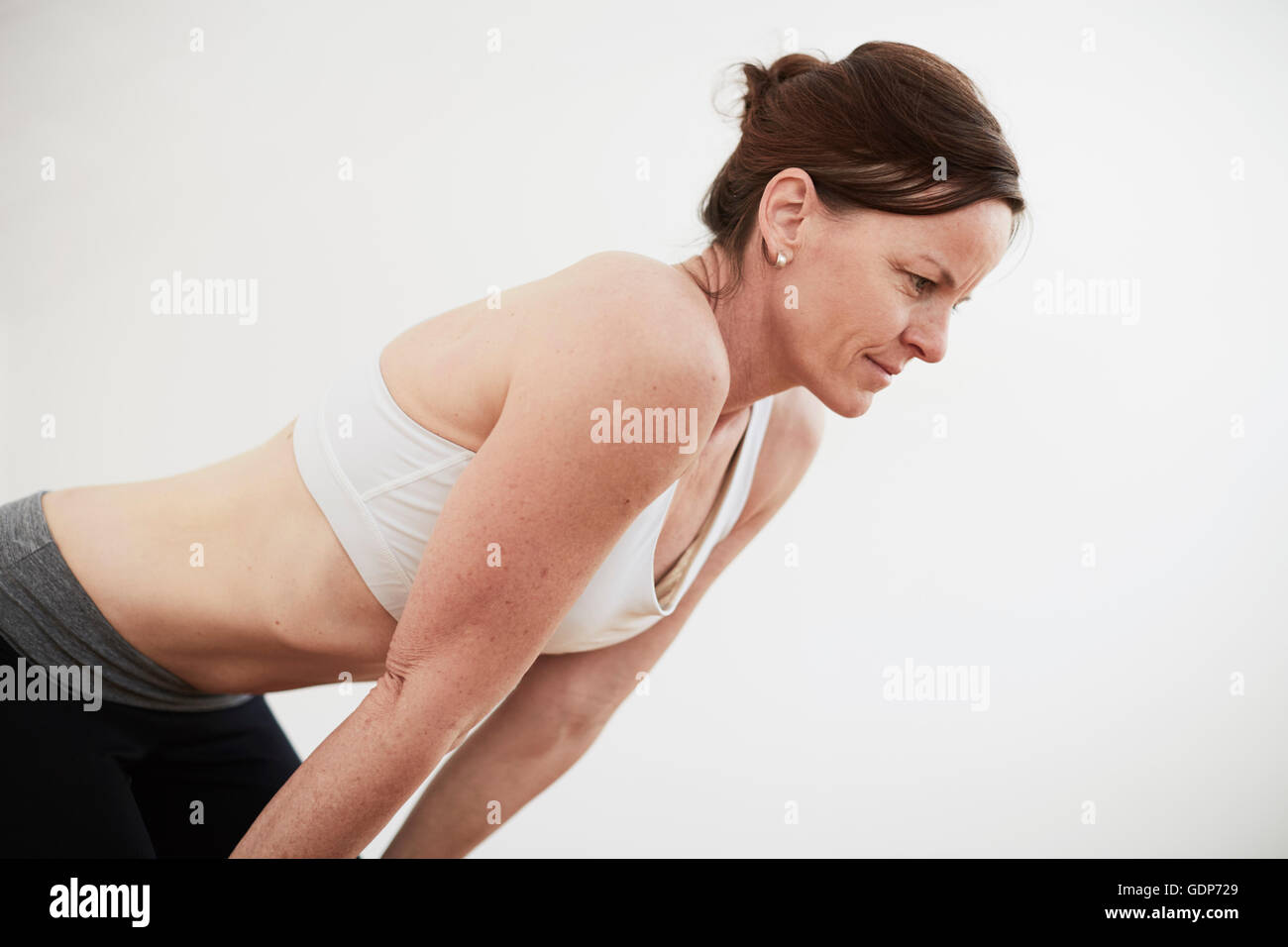 Mujer en ejercicio studio vistiendo crop top doblarse hacia adelante Foto de stock