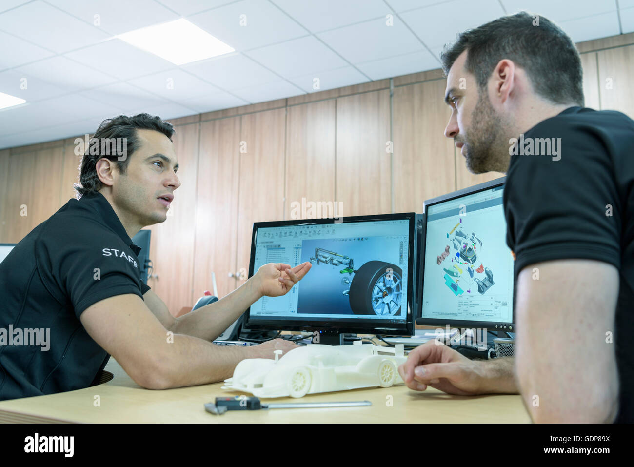 Ingenieros trabajan con imágenes de diseño CAD en la fábrica de automóviles de carreras Foto de stock