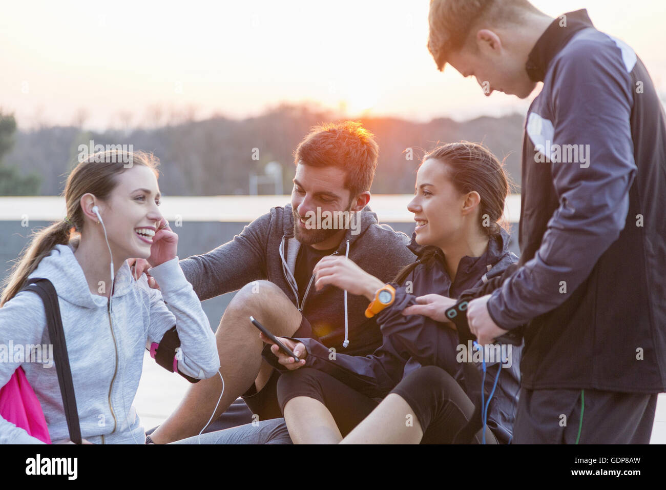 Cuatro amigos, vistiendo ropa deportiva, conversando, exteriores Foto de stock