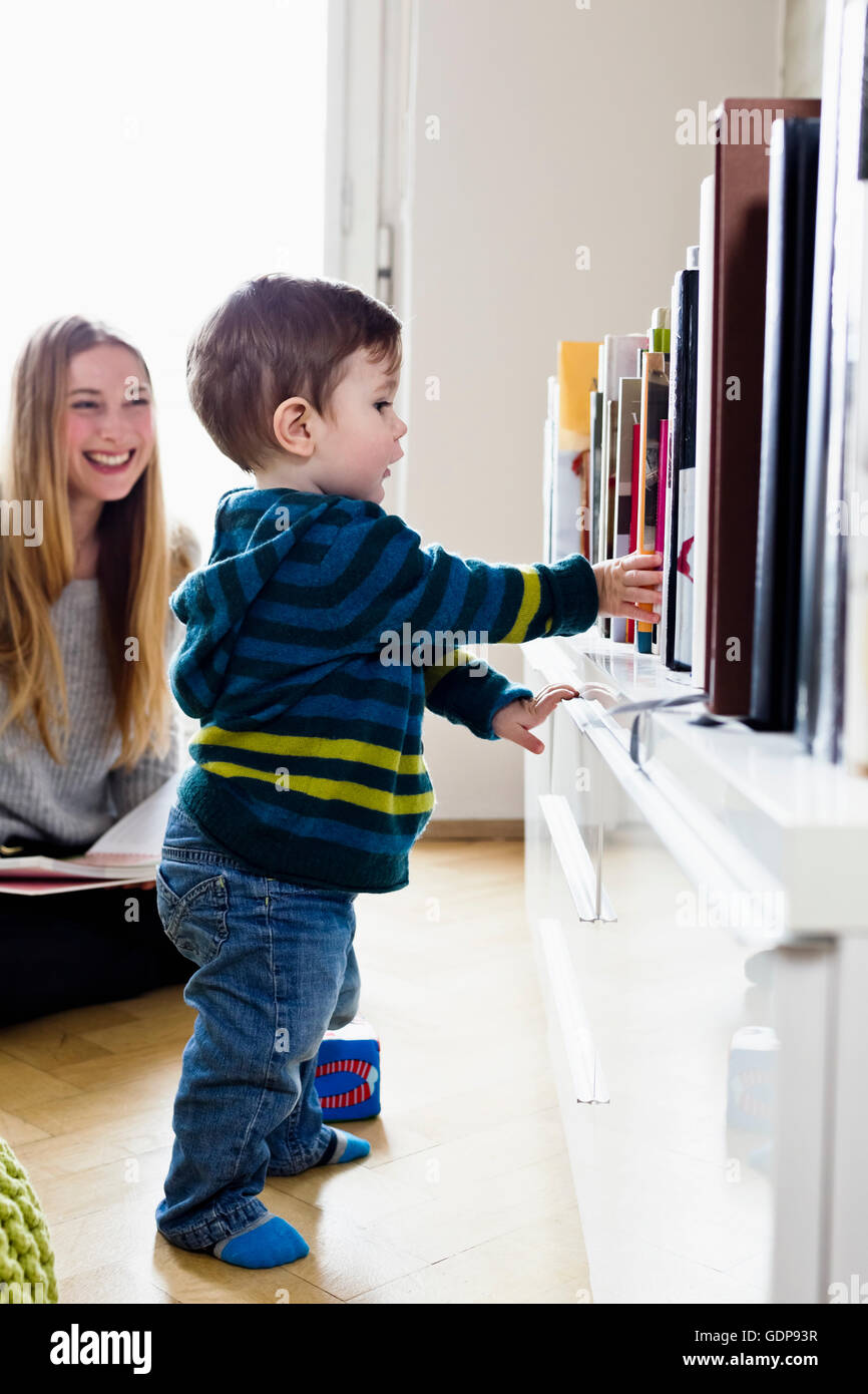 Mujer adulta media viendo hijo tomar primeros pasos Foto de stock