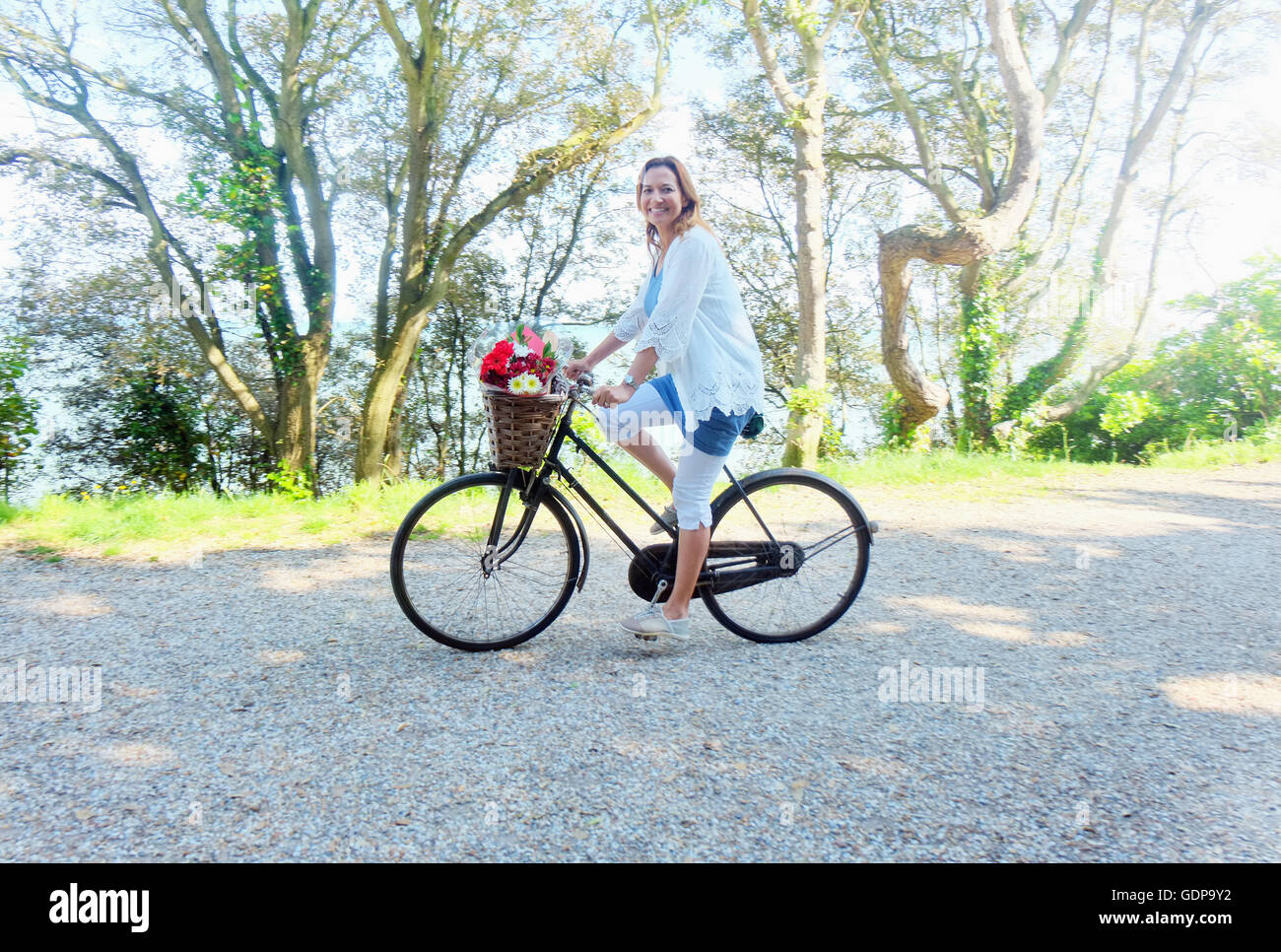 Mujer en bicicleta mirando a la cámara sonriendo Foto de stock