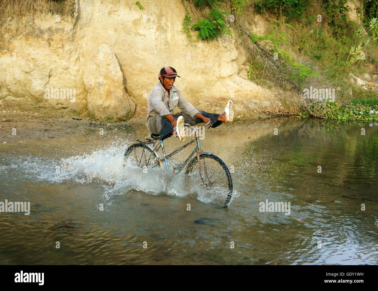 PHAN RANG, VIET NAM, hombre asiático montando bicicleta, gente corriente transversal a través del agua con la piedra, el estilo de vida a la población pobre rural vietnamita Foto de stock