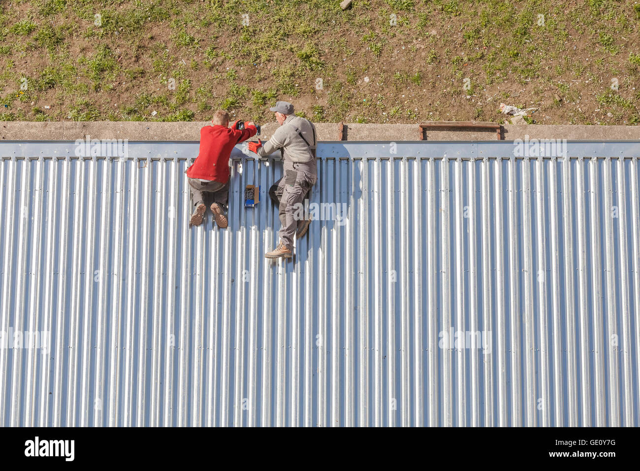 Szczecin, Polonia - Abril 07, 2016: Los trabajadores reparando una tienda techo hecho de planchas de metal corrugado, fotografía tomada desde arriba. Foto de stock