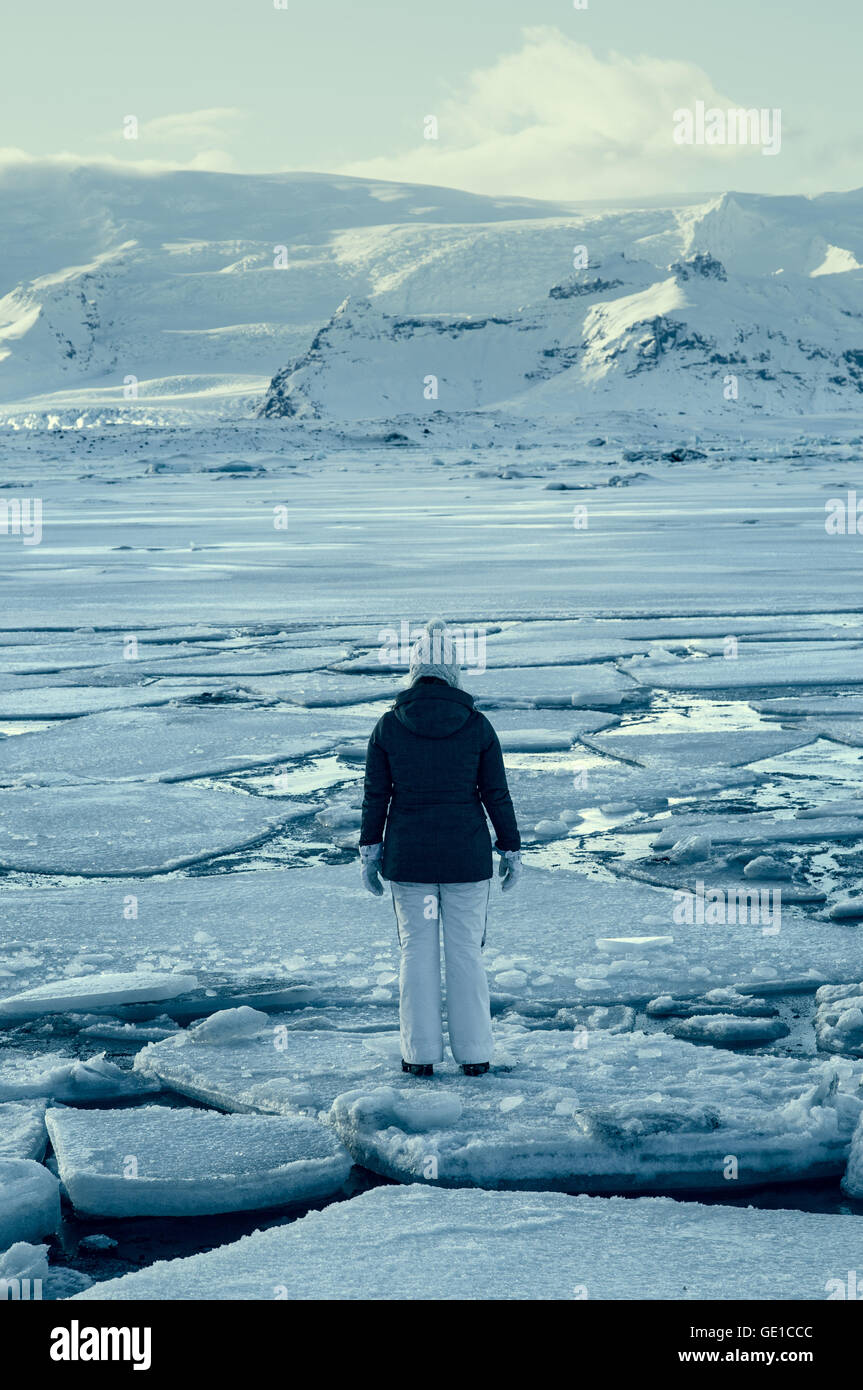 Mujer de pie sobre la banquisa en el lago congelado, Islandia Foto de stock