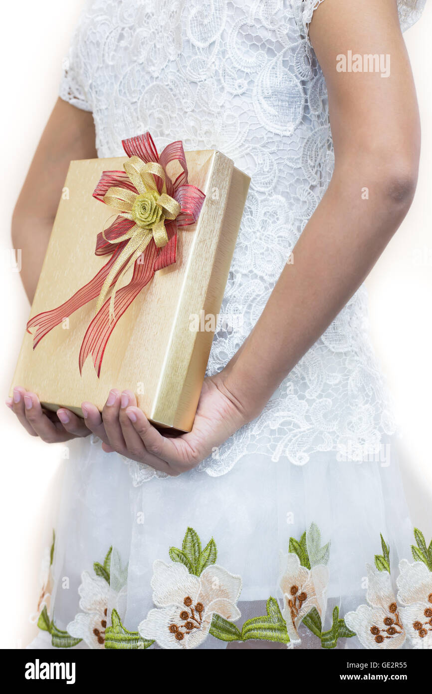 La mujer en blanco un regalo escondido detrás de su espalda. Foto de stock