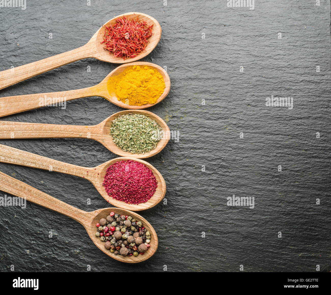 Variedad de coloridas especias en las cucharas de madera. Foto de stock