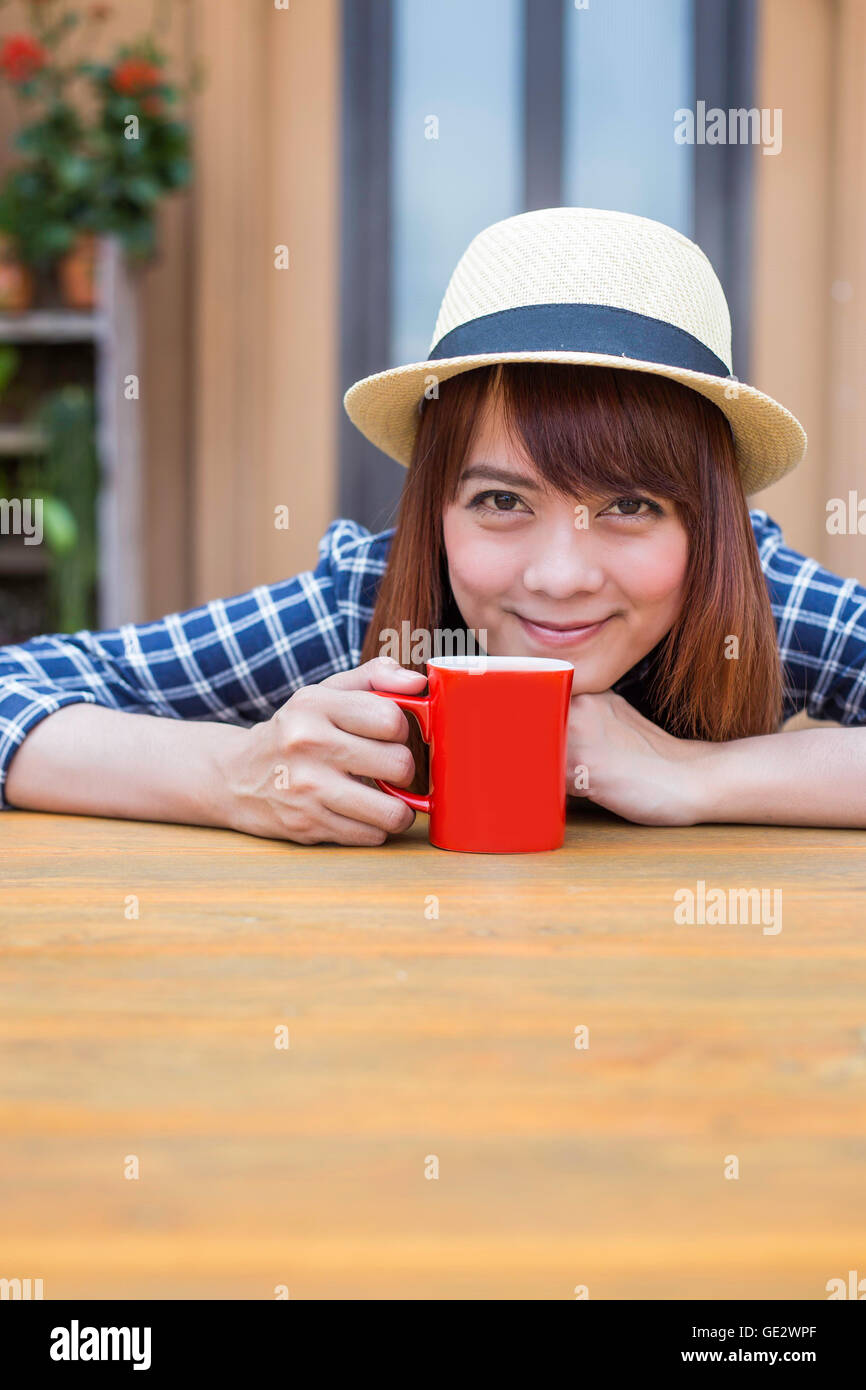 Lleve puesto un sombrero mujer sentada en el exterior con la bebida caliente relajarse Foto de stock