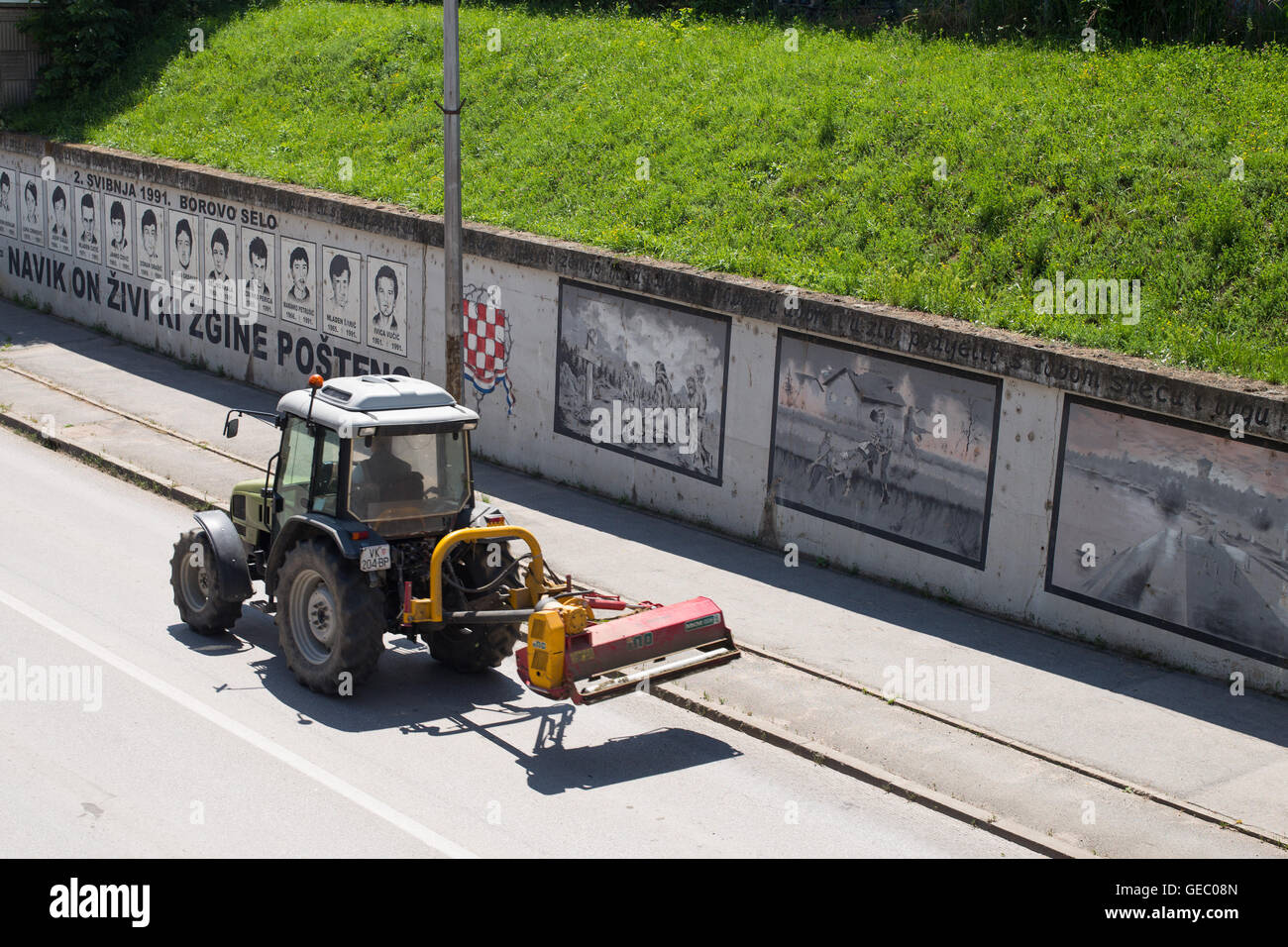 Un tractor pasando delante de Borovo Selo Memorial muro: "Quien muere en honestidad - vive eternamente" Foto de stock
