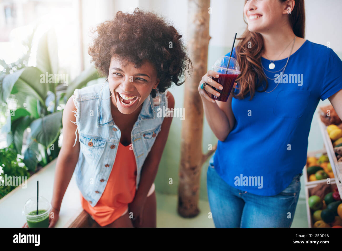 Retrato de mujer joven en alegre juice bar con un vaso de jugo fresco. Amigos disfrutando de un bar de zumos. Foto de stock