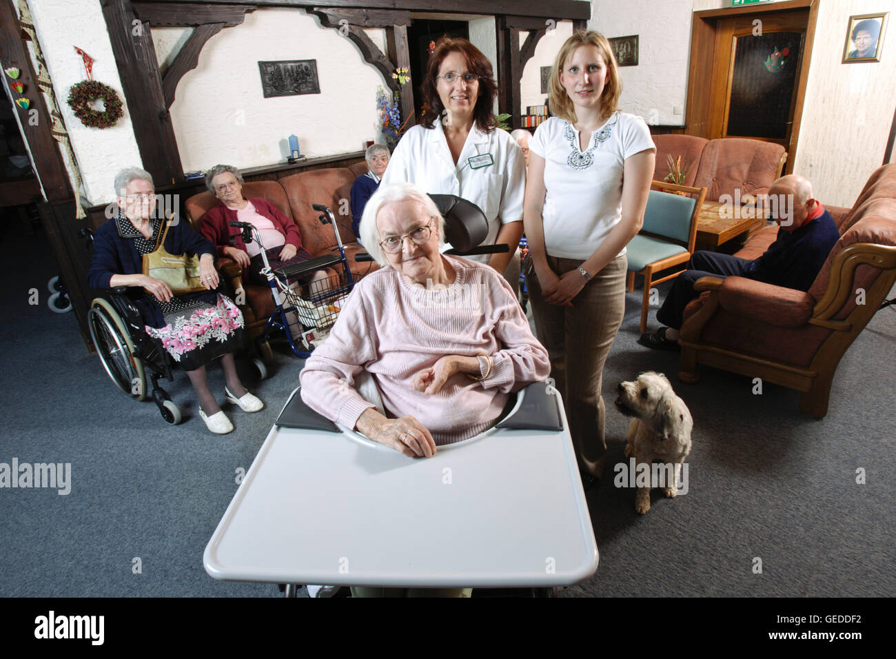 Los residentes y cuidadores, el personal de enfermería en la sala común de un hogar de ancianos Foto de stock