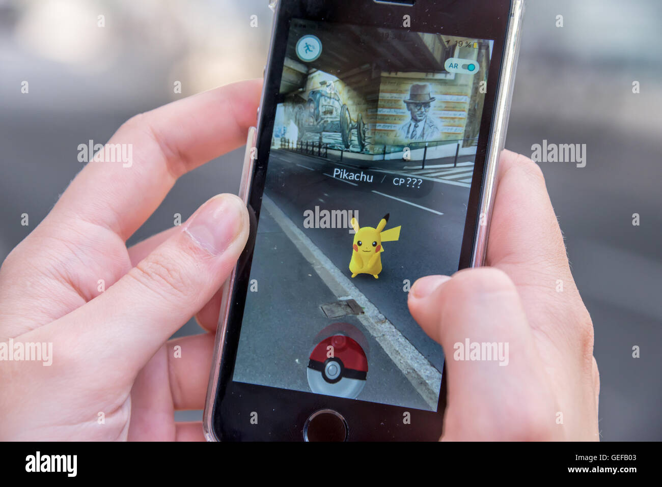 CHAVILLE, Francia - 24 de julio: Apple iPhone5s con Pikachu de Pokemon ir aplicaciones, las manos de un adolescente jugando en la primera da Foto de stock