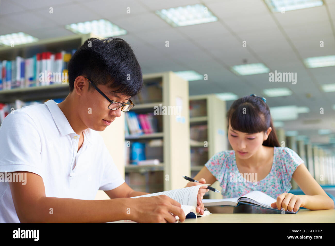 Los jóvenes asiáticos o estudiantes universitarios chinos estudian juntos en la biblioteca Foto de stock