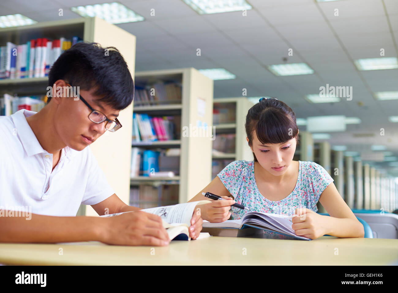 Los jóvenes asiáticos o estudiantes universitarios chinos estudian juntos en la biblioteca Foto de stock