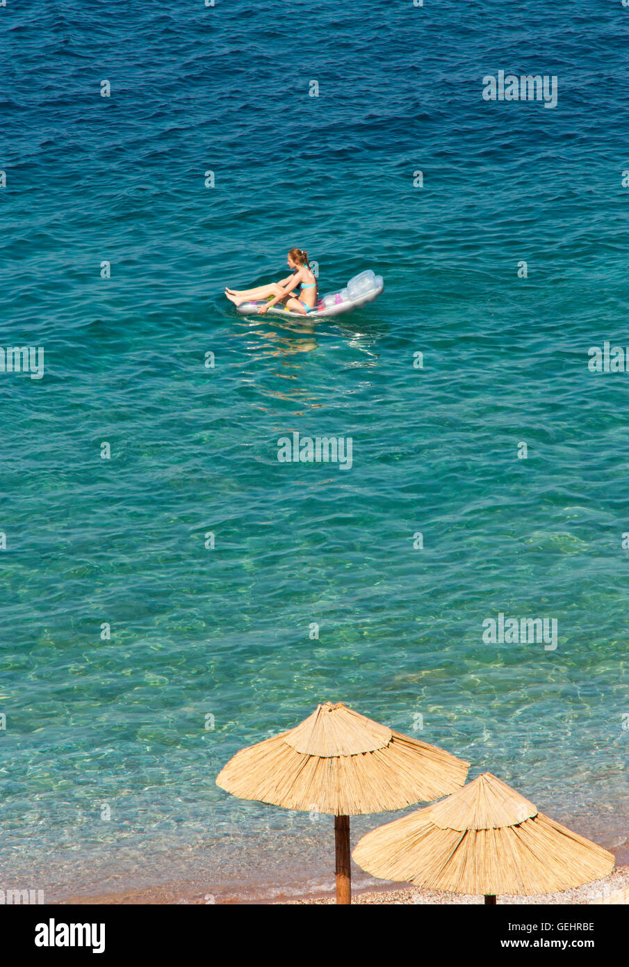 Joven en playa colchón inflable en el mar va desde la orilla Foto de stock