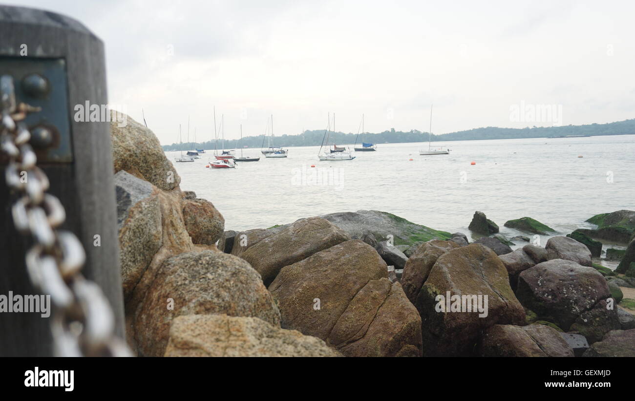 Vista de los barcos detrás de las rocas, en el paseo marítimo. Foto de stock
