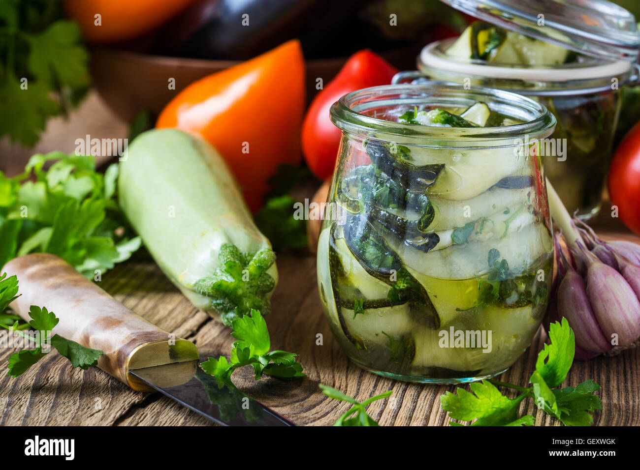 Calabacín enlatadas y verduras frescas. Rodajas de calabacín con perejil y ajo, verduras caseras conserva en frasco de vidrio Foto de stock