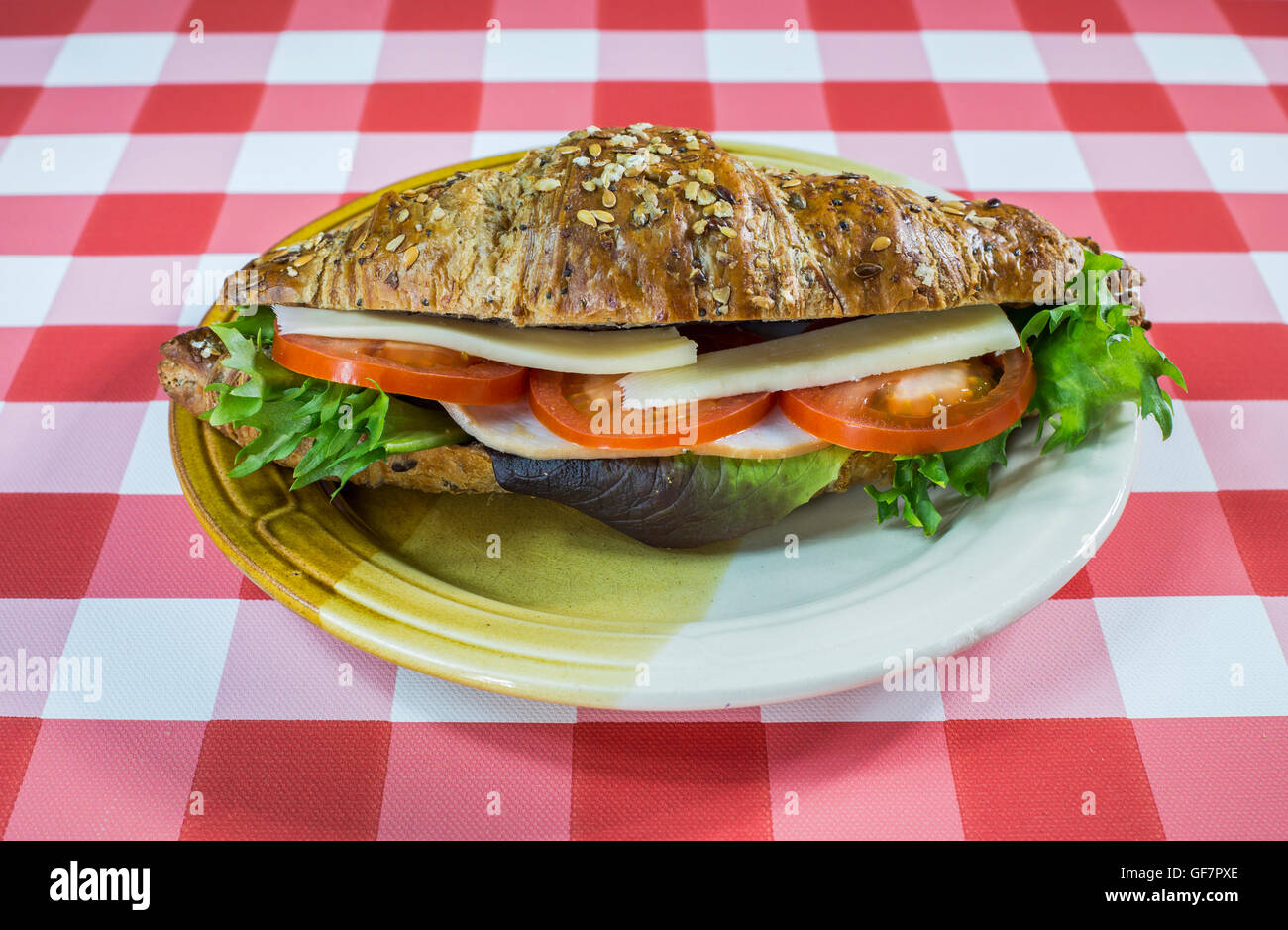 Cutre croissant sándwich en un mantel a cuadros. Foto de stock