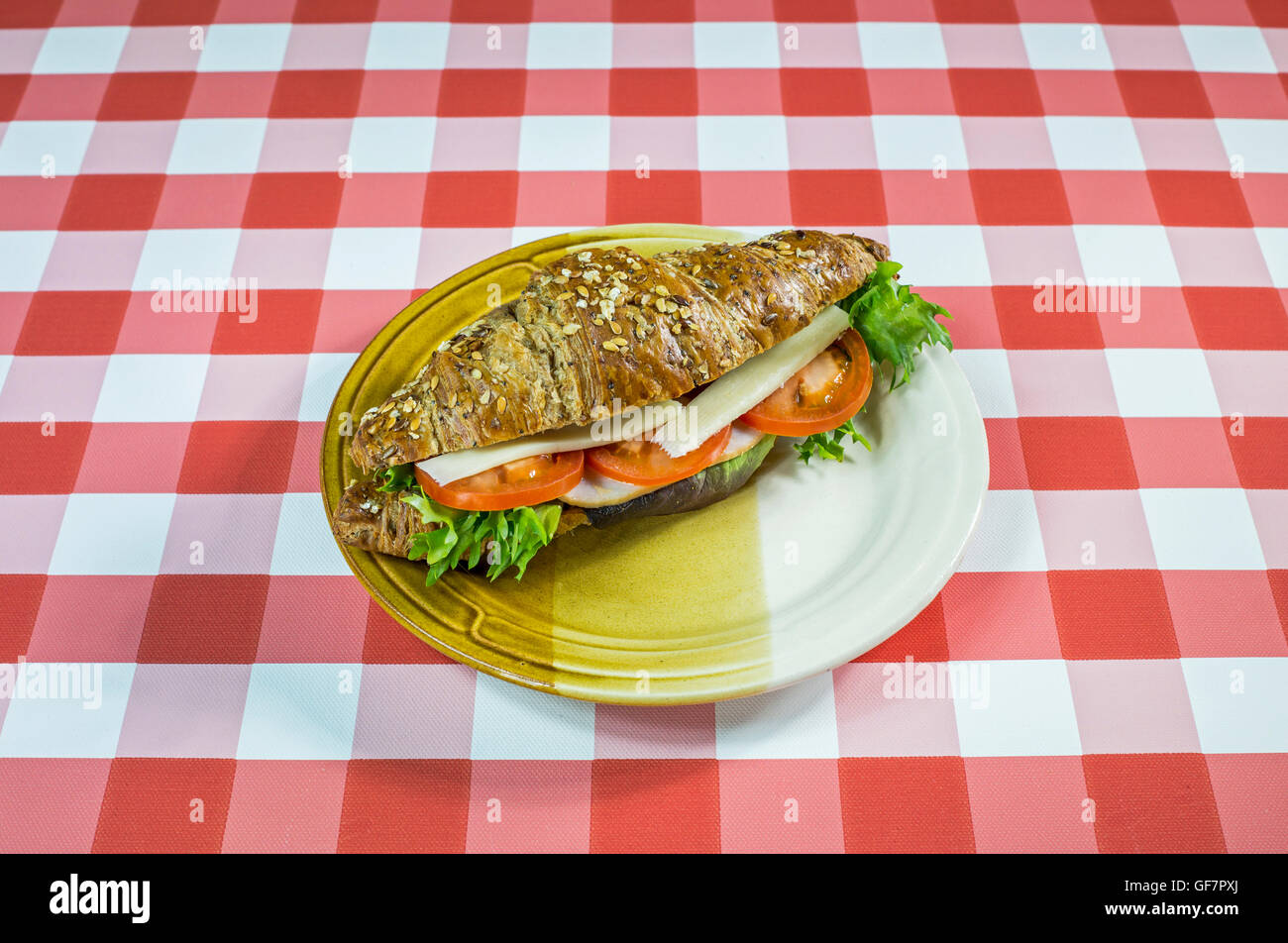 Cutre croissant sándwich en un mantel a cuadros. Foto de stock