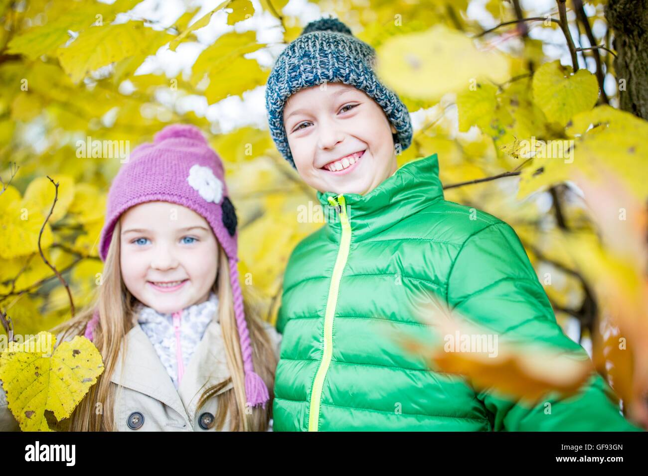 Modelo liberado. Los niños de pie junto a plantas de otoño y sonriente, retrato. Foto de stock