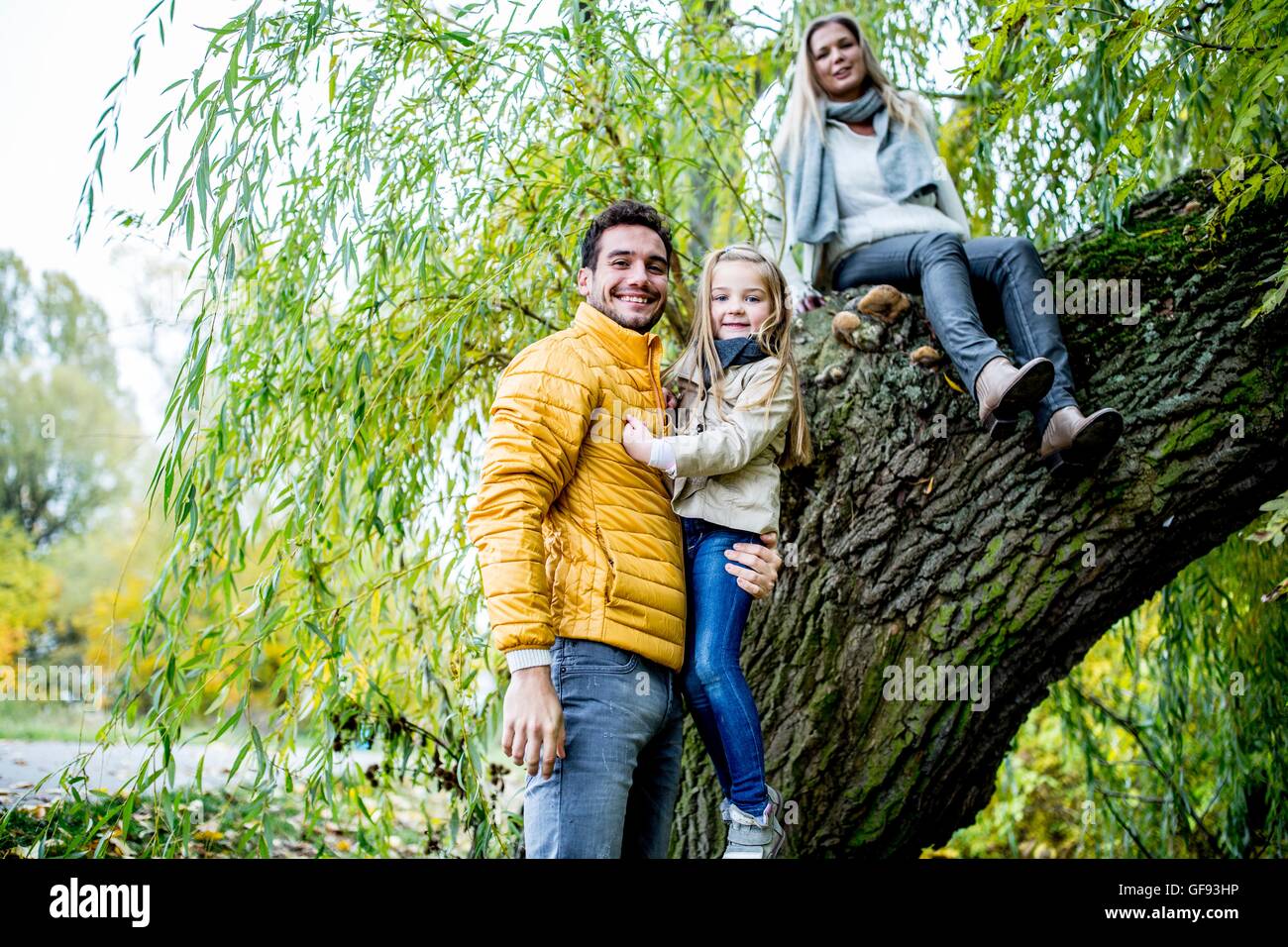 Modelo liberado. Padre llevar a su hija, la Madre sentada en el árbol, sonriendo, retrato. Foto de stock