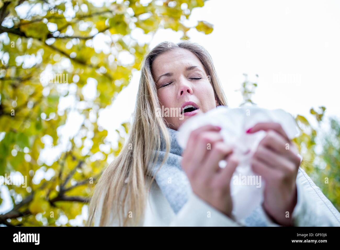 Modelo liberado. Mujer joven acerca a estornudar, los ojos cerrados. Foto de stock