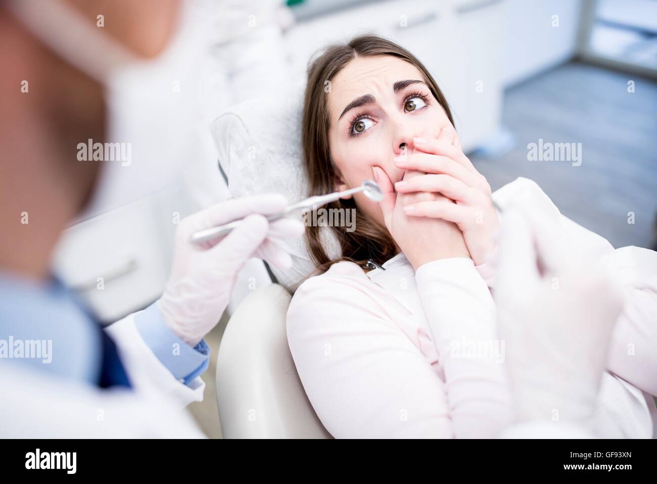 Modelo liberado. Conmocionado paciente mirando dentista dentista en la clínica. Foto de stock