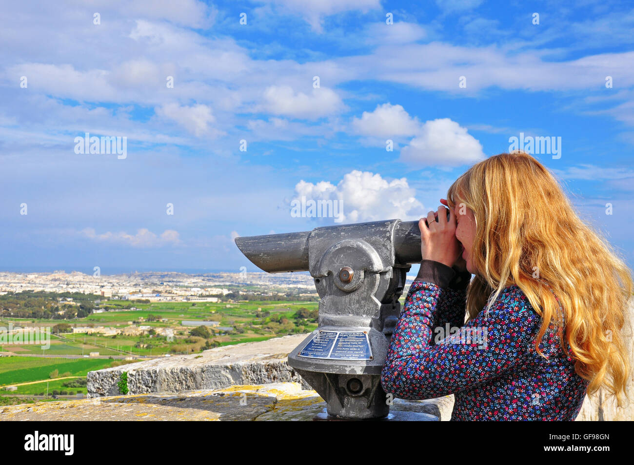 Cabello largo Blondy chica busca en el telescopio. Las islas maltesas Foto de stock