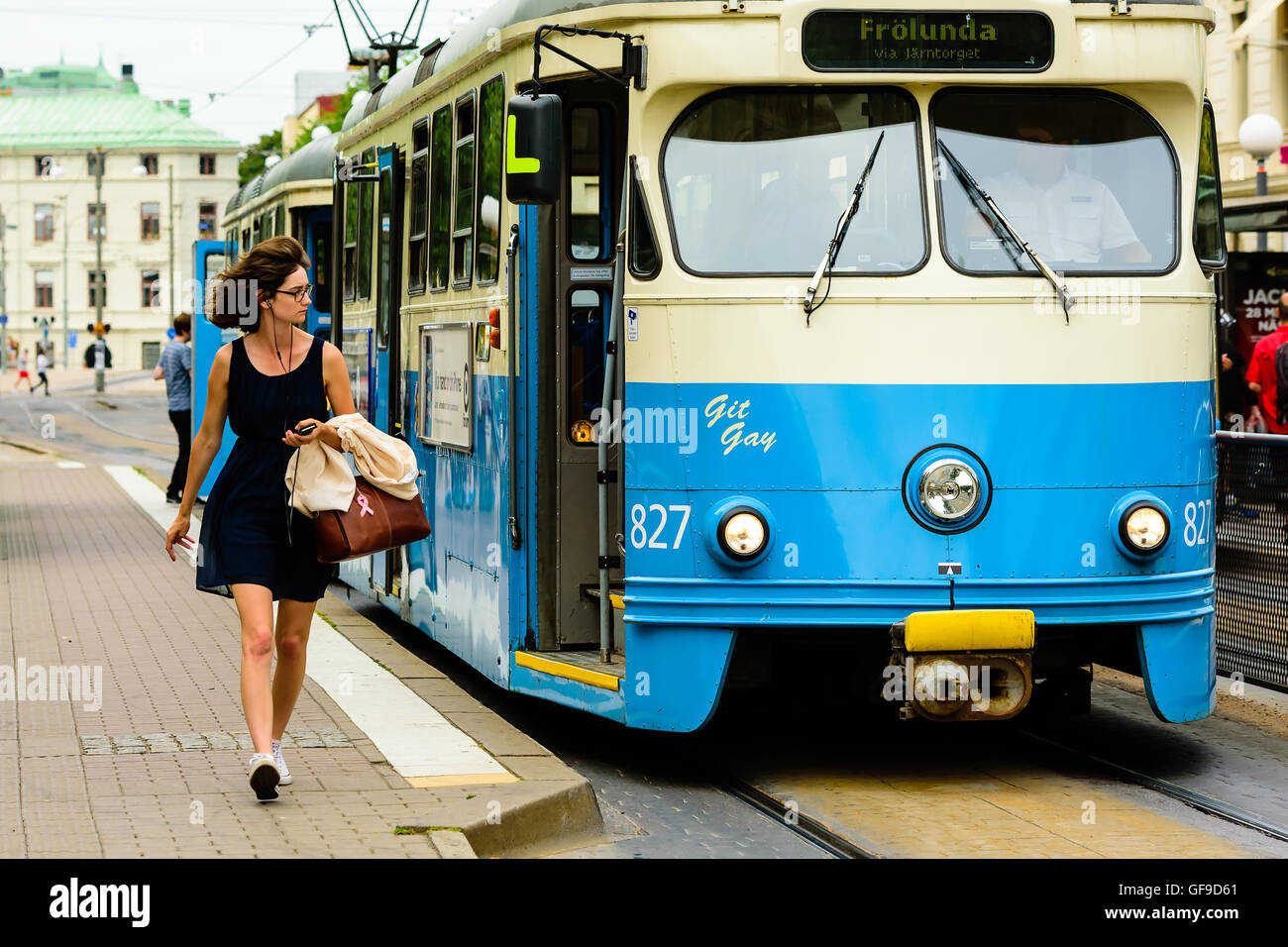 En Goteborg, Suecia - Julio 25, 2016: La gente real en la vida cotidiana. Mujer preciosa en vidrios caminando al lado de un tranvía eléctrico. Foto de stock