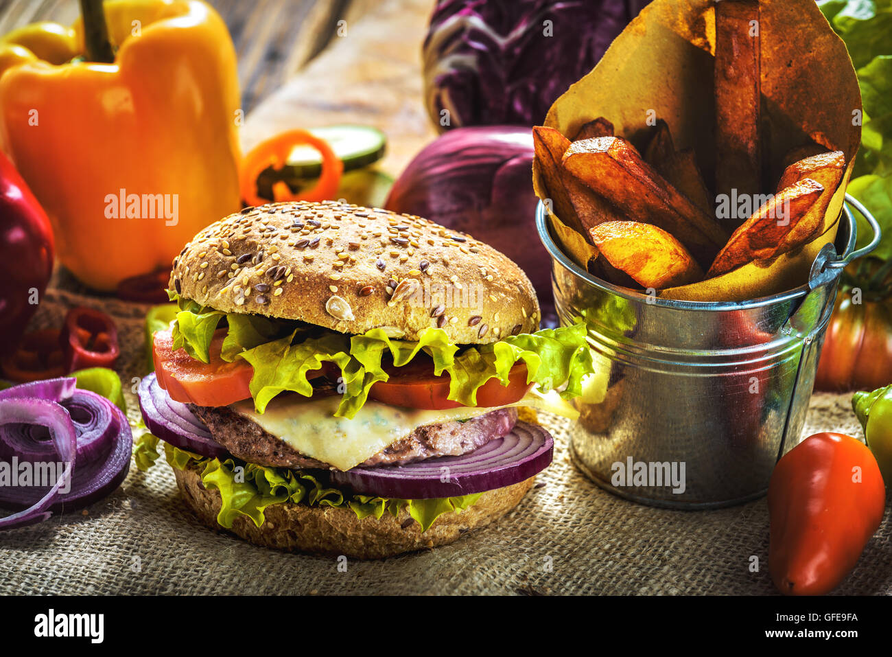 Fragante y sabrosa carne de hamburguesa en un saludable pan integral. Con tomate fresco, cebolla y lechuga con la adición de f Foto de stock