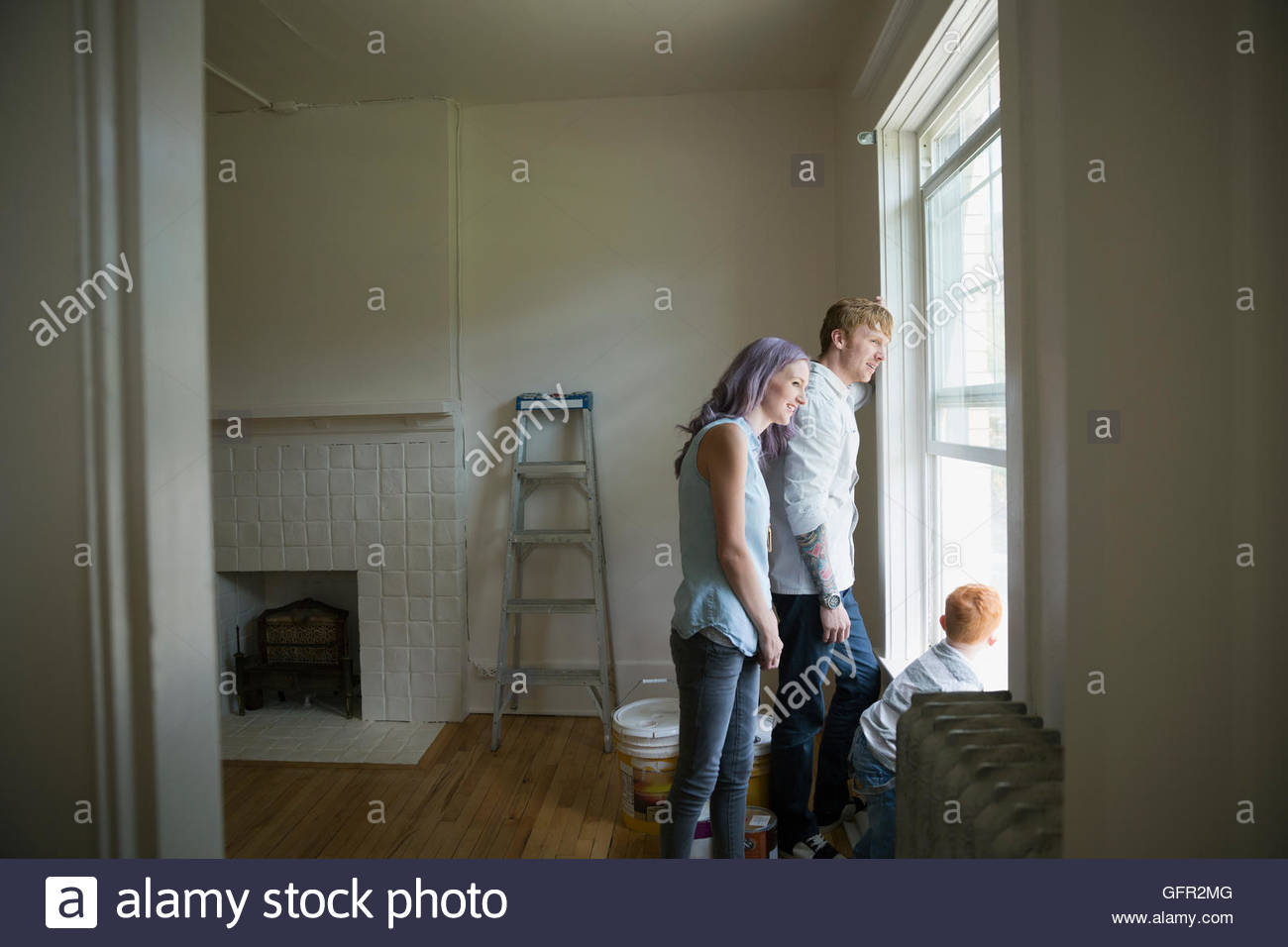 Familia Joven mirando por la ventana en la nueva casa Foto de stock