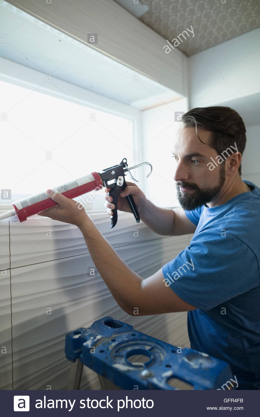 Hombre utilizando pistola de calafatear para home improvement project Foto de stock