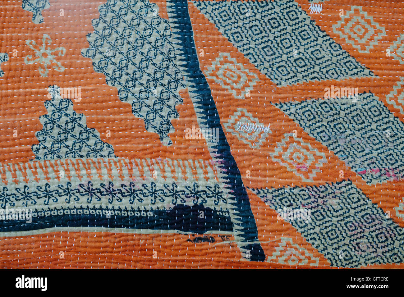 Cierre de un azul y crema de naranja colcha hecha de tela cosida guateado vintage y tejidos antiguos Foto de stock