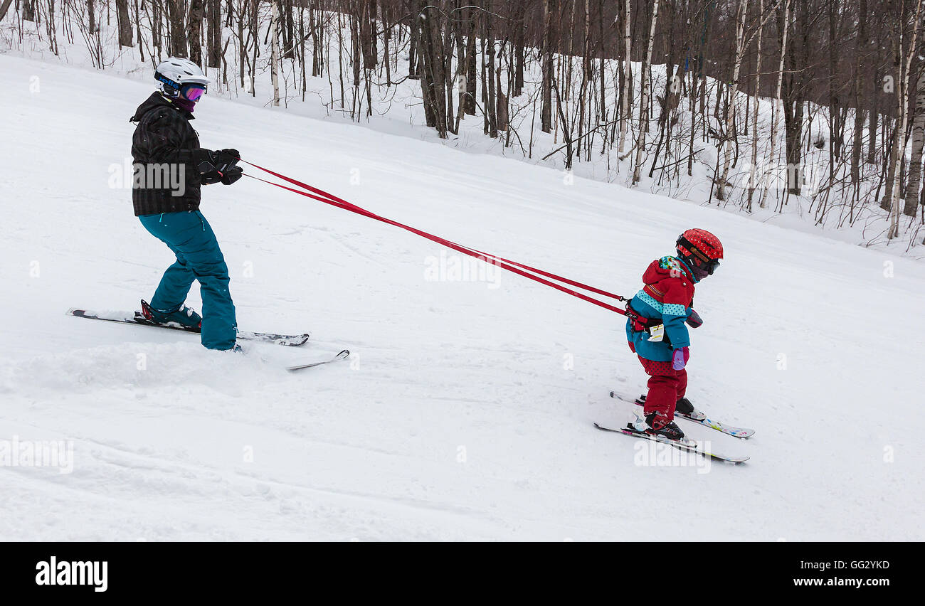 Mont Tremblant, Quebec, Canadá - 9 de febrero de 2014: una madre está enseñando a su joven hija a esquiar bajando una pendiente fácil. Foto de stock