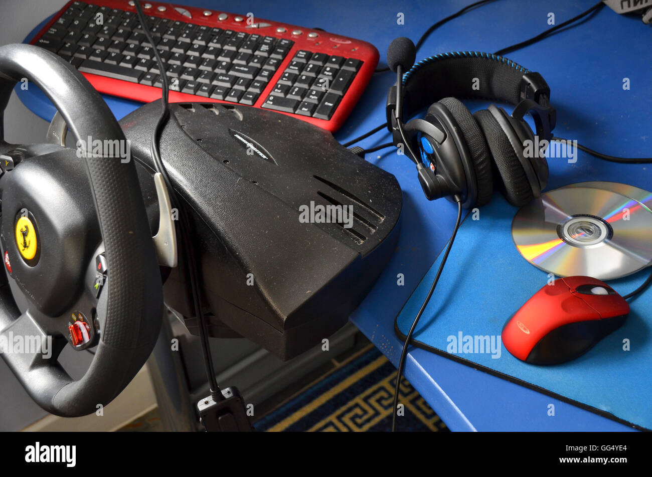La plataforma de juegos de ordenador - incluye volante montado sobre una mesa, teclado, auriculares, DVDs, una roja y una alfombrilla de ratón de desplazamiento. Foto de stock