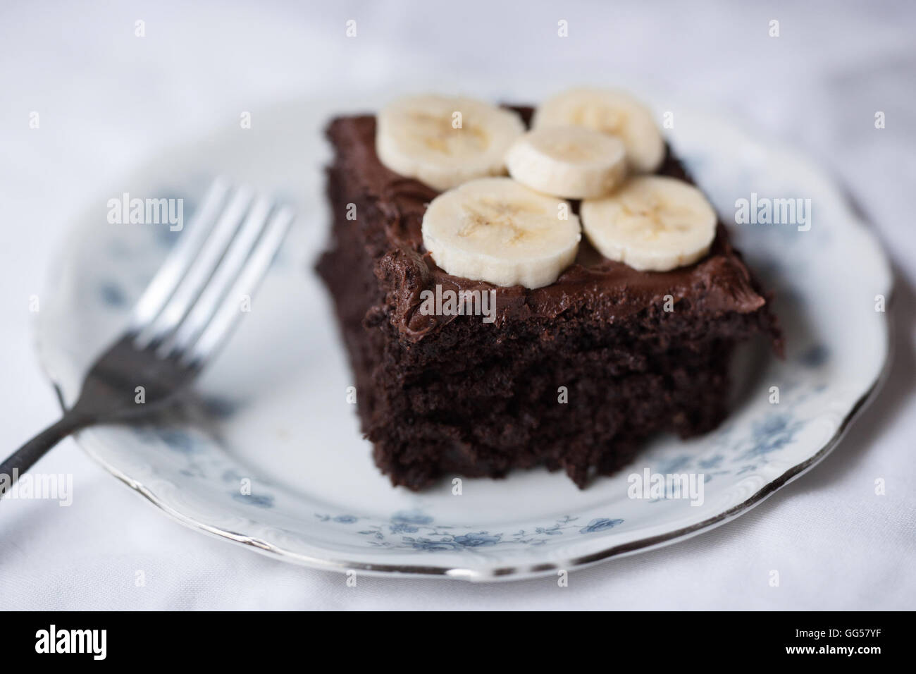 Tarta de chocolate orgánico rodajas de plátano azul blanco China horquilla glaseado de Chocolate Fotografía de alimentos Foto de stock