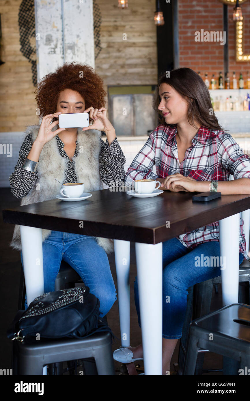 Amigas tomando una fotografía con la cámara del teléfono en el cafe Foto de stock