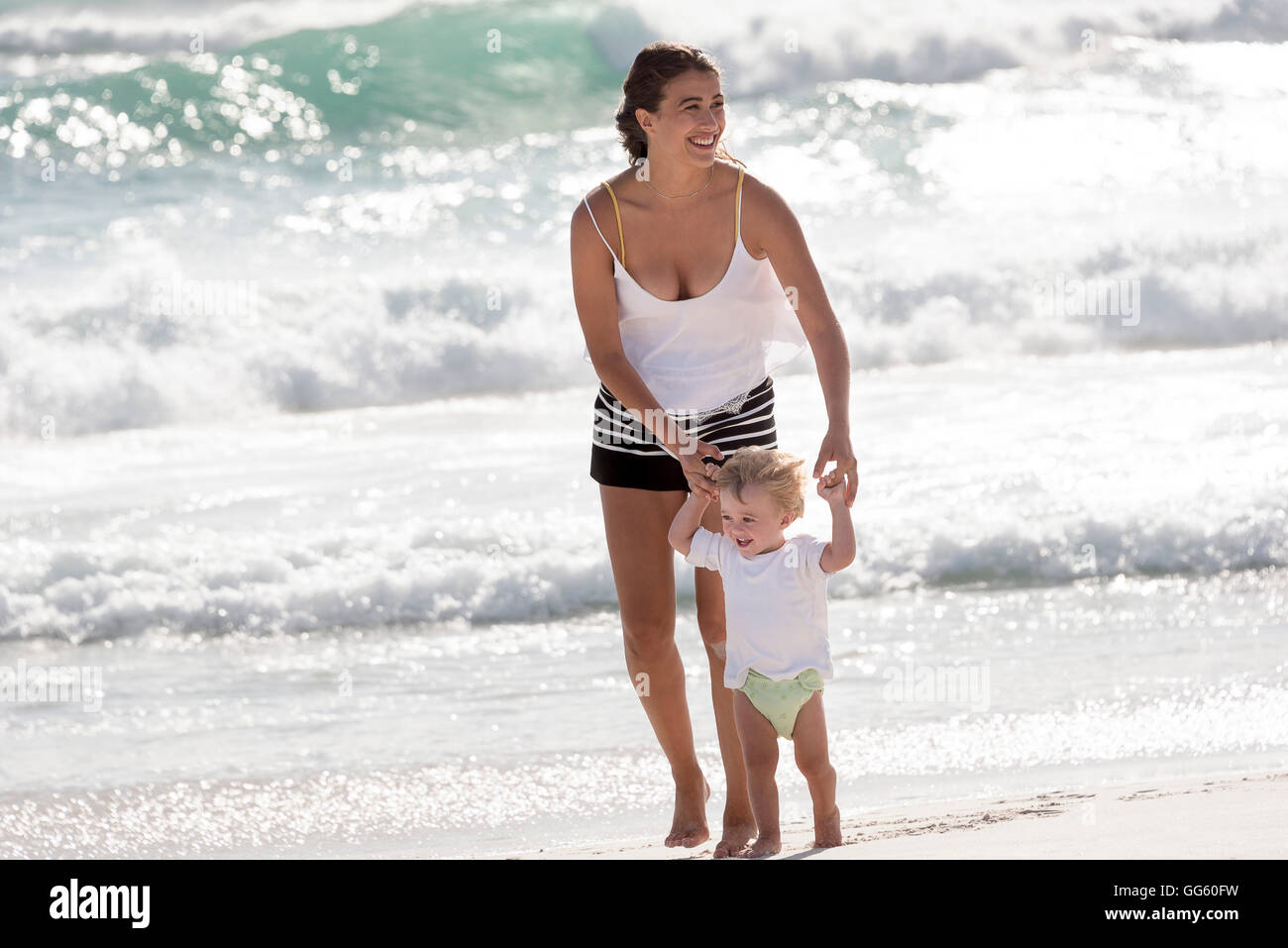 Feliz madre con su pequeño hijo caminar en la playa Foto de stock