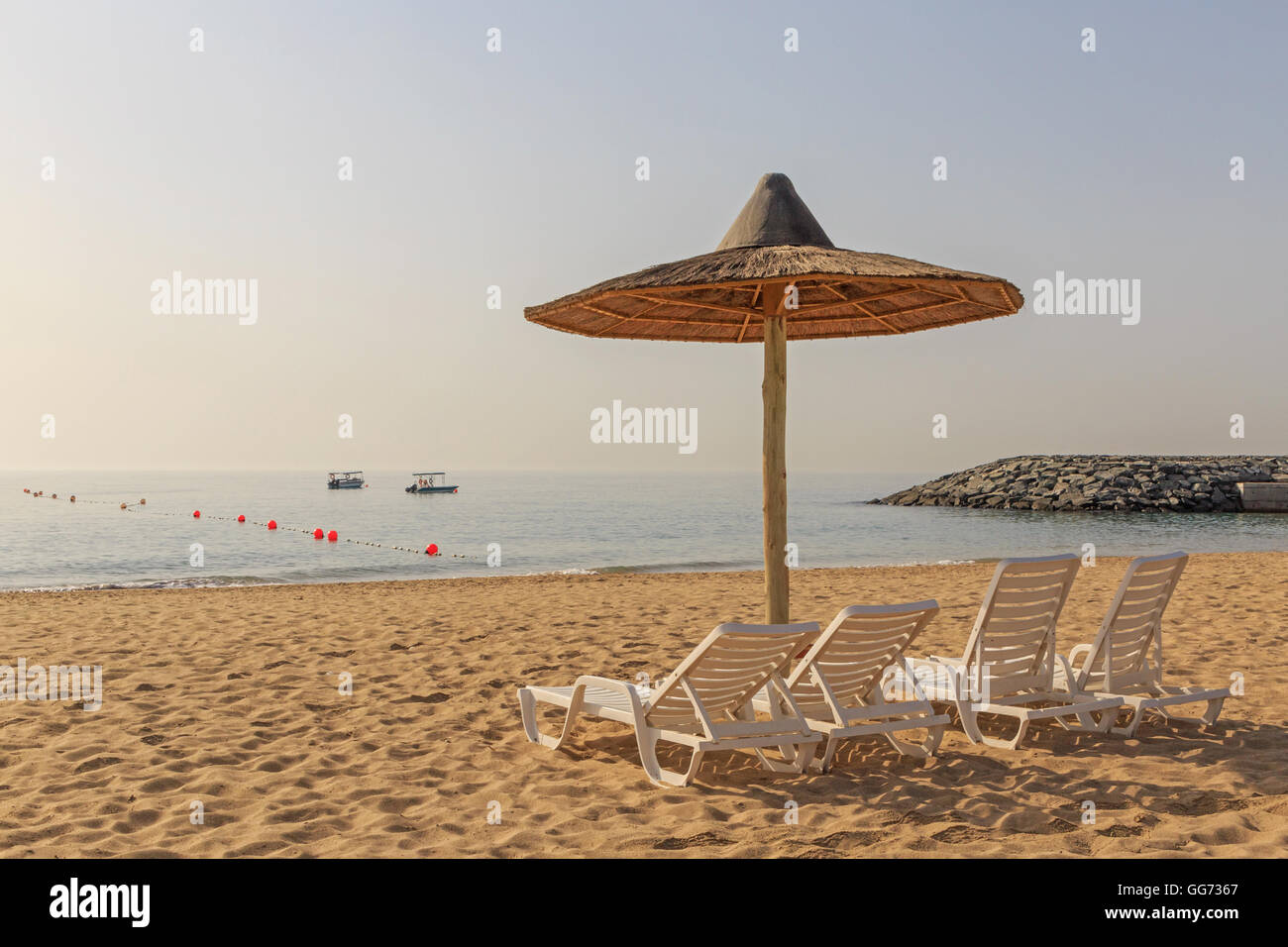 Vivienda sombrilla y sillas en la playa en Fujairah Foto de stock