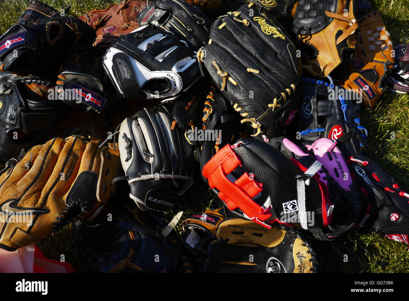 Montones de béisbol bien utilizada manoplas para niños y adultos amontonado  en césped en el sol Fotografía de stock - Alamy