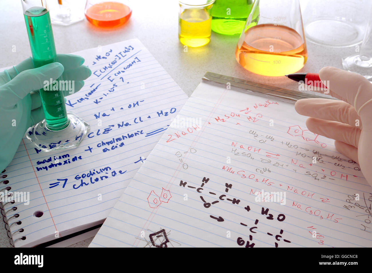 Scientist sosteniendo un bolígrafo sobre fórmulas de química en cuadernos  escritos a mano para ensayo de comparación de notas con un técnico de  laboratorio Fotografía de stock - Alamy
