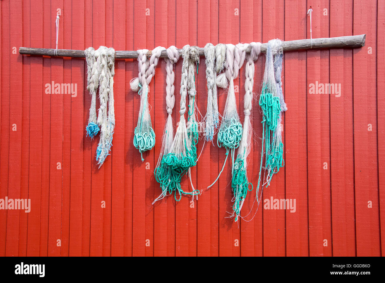 Redes de Pesca azul verde colgando de la pared de madera pintados en rojo Foto de stock