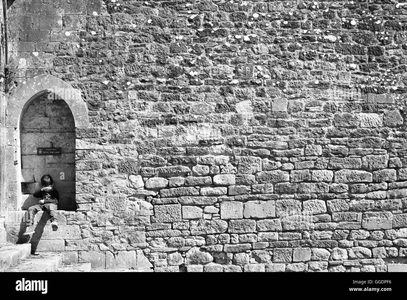 Pequeño muchacho sentado en un nicho en la pared o en la Abadía de Beaulieu Beaulieu, Nuevo Bosque UK Foto de stock