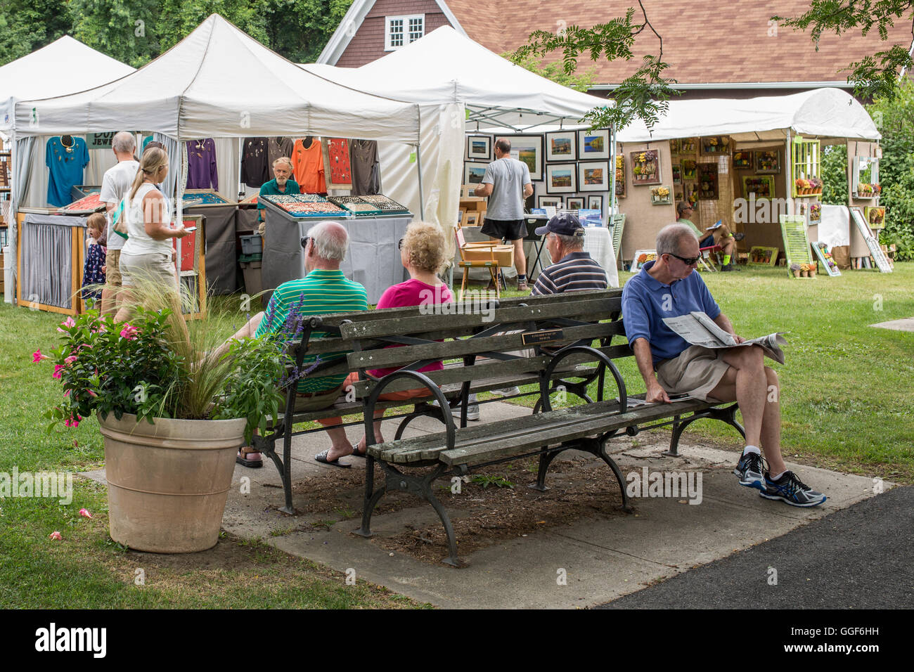La gente sentada en un banco en una muestra de arte y artesanía en Lenox, MA Foto de stock