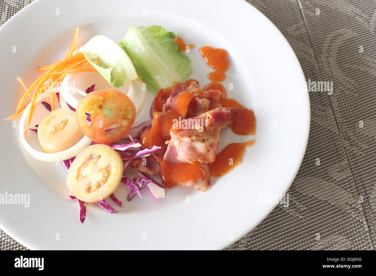 Ensaladas de verduras y salsa picante en un plato blanco en la tabla de alimentos. Foto de stock